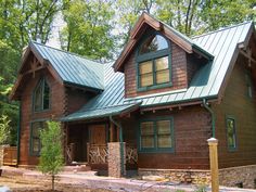 a log home with green shingles on the roof