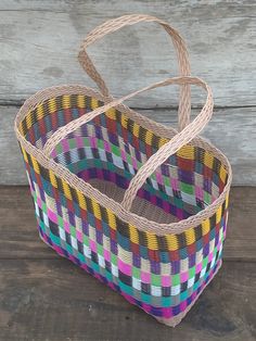 a multicolored woven basket sitting on top of a wooden floor