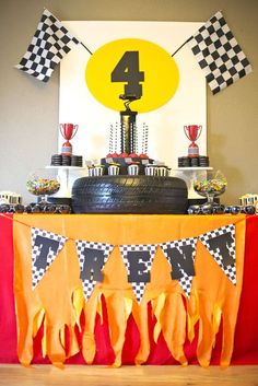 a birthday cake and cupcakes are displayed on a table in front of a racing theme