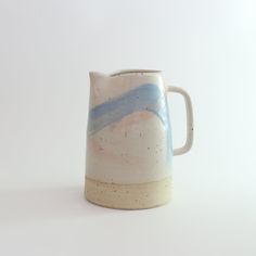 a white and blue ceramic pitcher sitting on top of a table