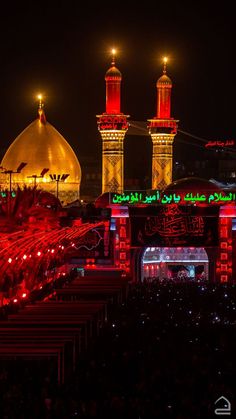 the lights are on at night in front of an ornate building with two large domes