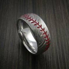 a baseball ring with red stitching on it sitting on top of a wooden table