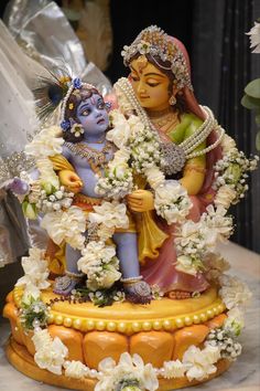 a statue of the hindu god and goddess with flowers in her hair is displayed on a table