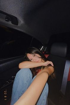 a woman sitting in the back seat of a car with her hand on her face