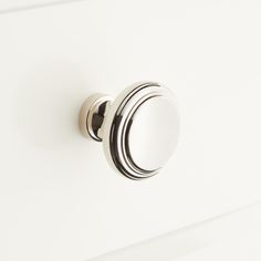 a close up of a door handle on a white cabinet