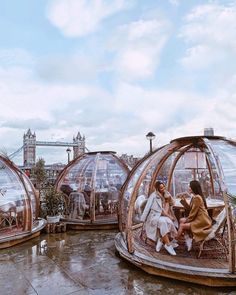 three people sitting in glass domes on top of a roof