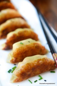 some food is sitting on a white plate with chopsticks in front of it