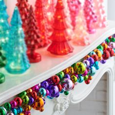 brightly colored christmas trees are displayed on a mantle