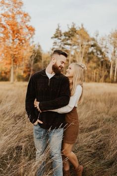 a man and woman are standing in the tall grass with their arms around each other