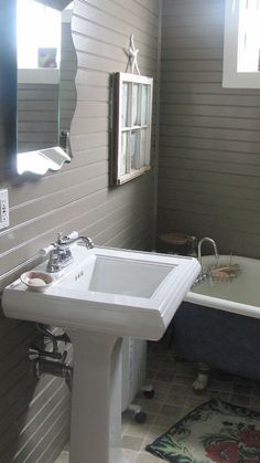 a white sink sitting under a bathroom mirror next to a bathtub with a blue tub underneath it