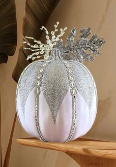 a white and silver decorative pumpkin on a shelf