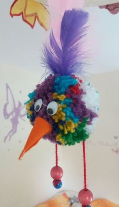 a colorful bird hanging from the ceiling with feathers on it's head and eyes