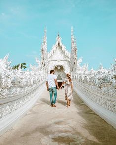 two people walking down a road in front of a white building