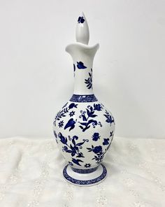 a blue and white vase sitting on top of a white tablecloth covered floor next to a wall