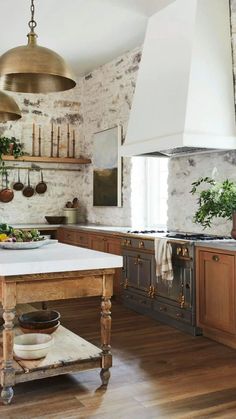 a kitchen with wooden floors and an island in the middle of it, surrounded by brick walls