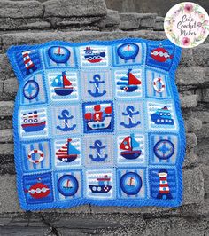 a crocheted blue blanket with boats and ships on it, sitting next to a stone wall