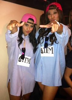 two girls in matching shirts and pink hats posing for the camera with their fingers up