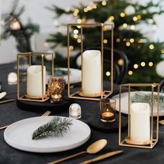 a table topped with candles and plates covered in gold trimmings next to a christmas tree