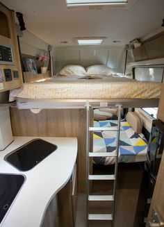 the interior of a camper with stairs leading up to the bed and desk area