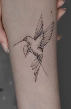 a small hummingbird tattoo on the left inner arm and wrist, it is black and white