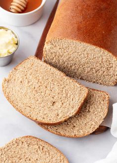 sliced loaf of whole wheat bread with butter and honey on the side next to it