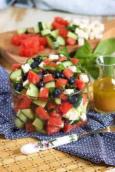 a salad with cucumbers, olives and blueberries in a glass bowl