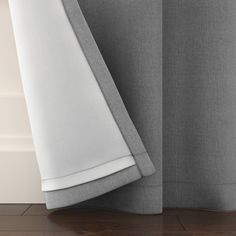 the side of a bed with a white sheet and grey sheets on top of it