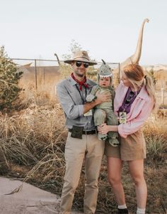 a man and woman standing next to each other in front of an animal statue with a dinosaur on it's head