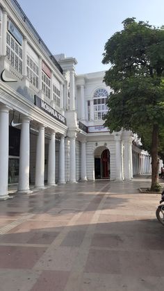 a motorcycle parked in front of a building with columns on both sides and a tree