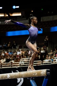 a woman is standing on a beam in front of an audience