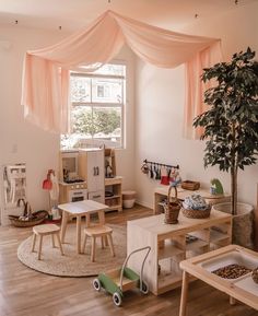 a child's playroom with wooden furniture and pink drapes over the windows