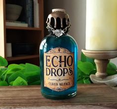 a blue bottle sitting on top of a wooden table next to a candle and green leaves