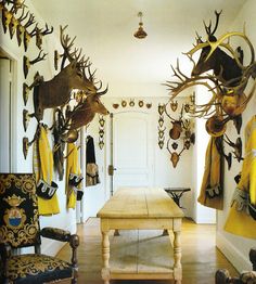 a room filled with lots of deer heads mounted to the wall next to a wooden table