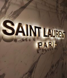 the entrance to saint laurent paris is lit up in gold and black letters on a marble wall