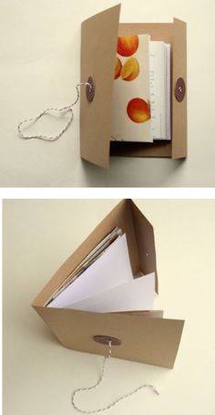 an open cardboard box with paper and string attached to the inside, on top of a white surface