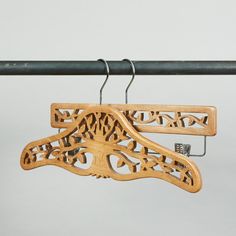 a pair of wooden clothes hangers on a metal rod with an intricately carved design