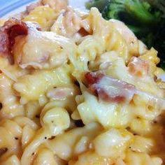 a plate with pasta, broccoli and bacon on it next to a fork