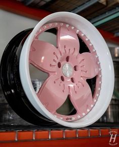 a pink and white wheel on top of a red shelf in a store or office