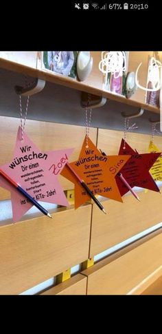 some paper stars hanging from the ceiling in front of a shelf with writing on them