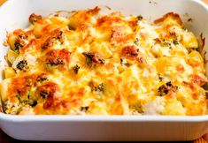 a casserole dish with broccoli and cheese in it on a wooden table