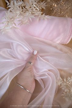 a woman's hand on top of a pink dress with white flowers in it