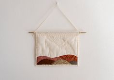 a white wall hanging with a patchwork quilt on it