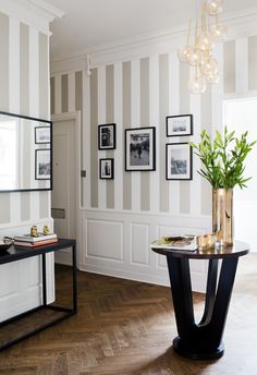 a living room filled with furniture and pictures on the wall next to a table in front of a mirror