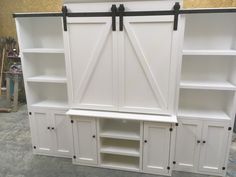 a white entertainment center with sliding doors and shelves