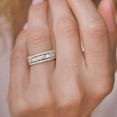 a woman's hand with two wedding bands on her finger and the ring has three diamonds in it