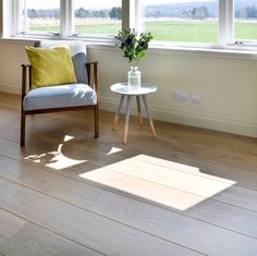 a chair and table sitting in front of two windows with the sun shining through them