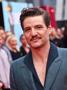 a man in a suit and tie posing for a photo on the red carpet at an event