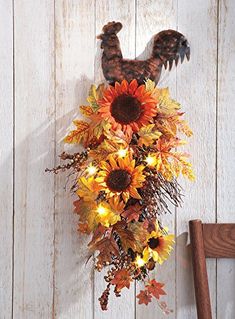 an arrangement of sunflowers and leaves hangs on the wall