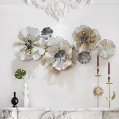 a white fireplace with metal flowers on the mantle