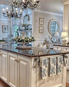 a chandelier hanging from the ceiling in a kitchen with white cabinets and an island